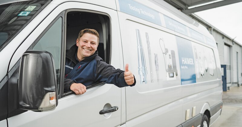 Man sitting in a van and raising his thumb up.